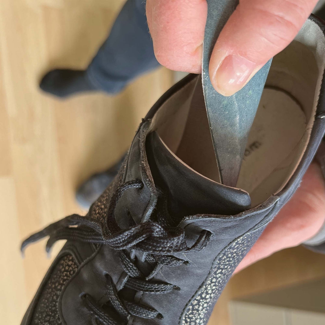 Zeigt, wie ein Schaumstoffpolster aus dem Schuh genommen wird